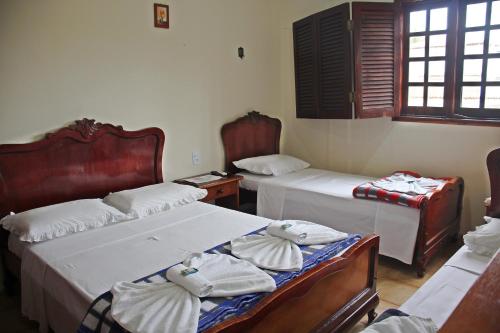 a bedroom with two beds and a table and windows at Pousada Solar Do Triunfo in Triunfo