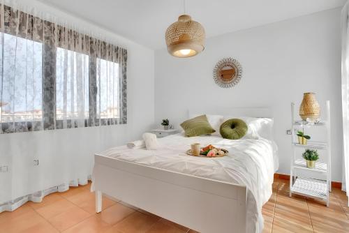 a white bedroom with a bed with a tray of food on it at Casa Bonita Lajares 2 in Lajares