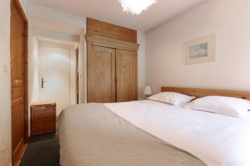 une chambre avec un lit blanc et une armoire en bois dans l'établissement Le Chamouny- Family Apt - Central - Quiet - Hikeing & Rock Climbing Close by, à Chamonix-Mont-Blanc