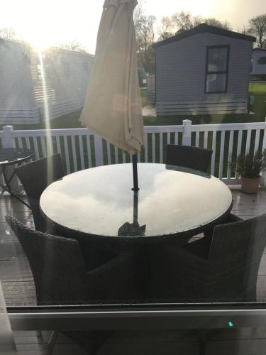 an umbrella sitting on a table on a patio at NEW FOREST Hoburne Bashley Holiday Park, Spacious Caravan Sycamore 201 Sleeps 6 in New Milton