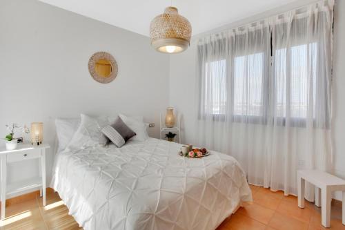 a white bedroom with a white bed and a window at Casa Bonita Lajares Fuerteventura in Lajares