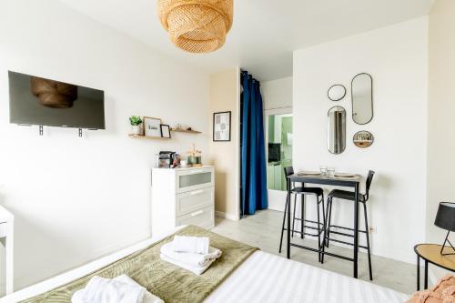 a bedroom with a bed and a kitchen with a table at L'Oasis - Studio à 350m de la mer & du centre ville in Saint-Nazaire