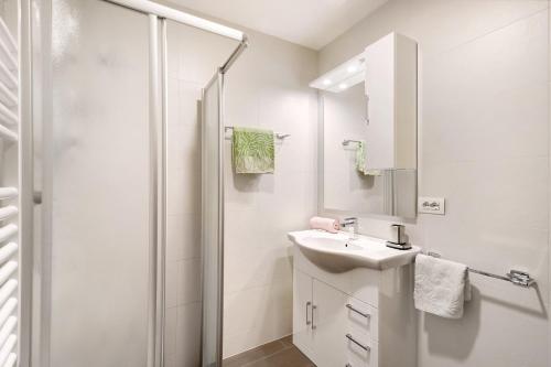 a white bathroom with a sink and a shower at Pension Waldheim Apartments in San Giacomo