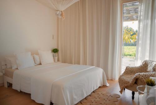 a white bedroom with a white bed and a window at La Farm Baleares in Santa Maria del Camí