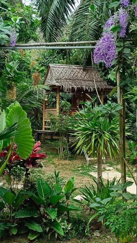 a garden with a bamboo hut with purple flowers at Rommai Forest Bungalows in Ko Lanta