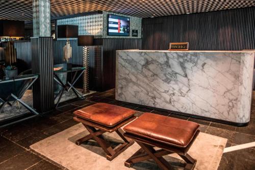 a lobby with two stools and a marble counter at Apollo Hotel Amsterdam, a Tribute Portfolio Hotel in Amsterdam