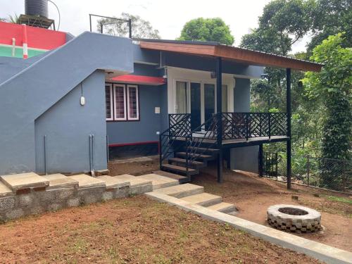 a small blue house with a staircase and a porch at The Grove in Devikolam