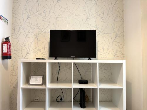 ein weißes Unterhaltungszentrum mit einem Fernseher darüber in der Unterkunft Casa De Baixo in Lissabon