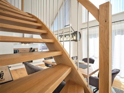 a wooden staircase in a room with a table and chairs at Gipfelblick Lodge 5 Pruggern by AA Holiday Homes in Pruggern
