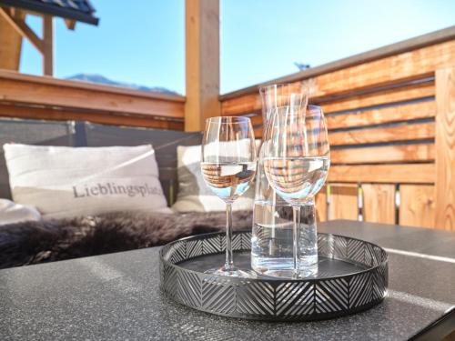 two glasses of wine on a tray on a table at Gipfelblick Lodge 5 Pruggern by AA Holiday Homes in Pruggern