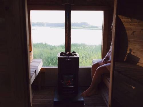 a woman sitting in a room with a fireplace in front of a window at STF Gysinge Wärdshus & Hotell in Gysinge