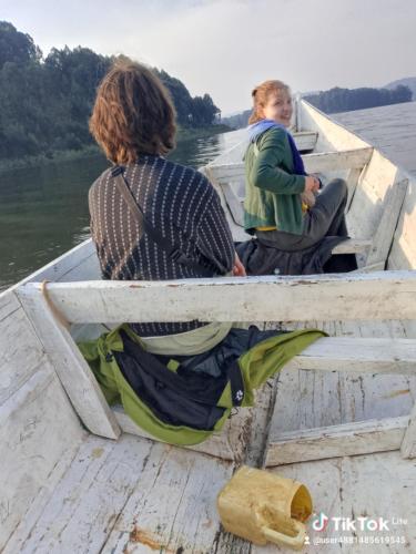 two people sitting in a boat on the water at Weaver Bird Hostel in Rubanda