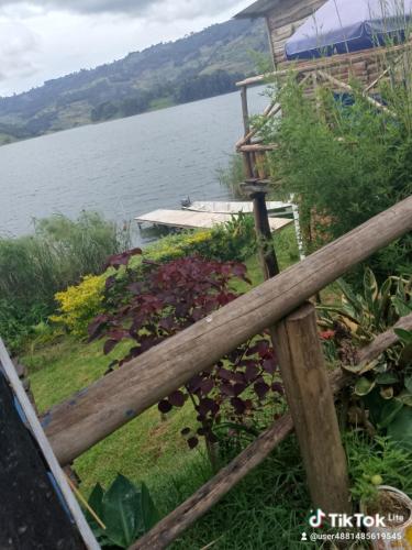 a wooden fence next to a body of water at Weaver Bird Hostel in Rubanda