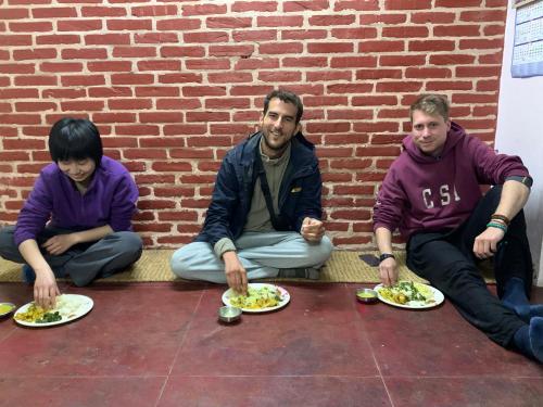 a group of people sitting on the floor with plates of food at Bhaktapur Homestay in Bhaktapur