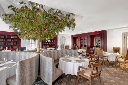 a restaurant with tables and chairs and a tree at Protea Hotel by Marriott Blantyre Ryalls in Blantyre