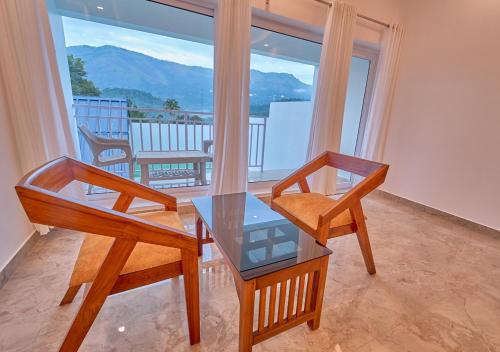 two chairs and a table in a room with a balcony at Ice Mist Pool Resort Munnar By VOYE HOMES in Munnar