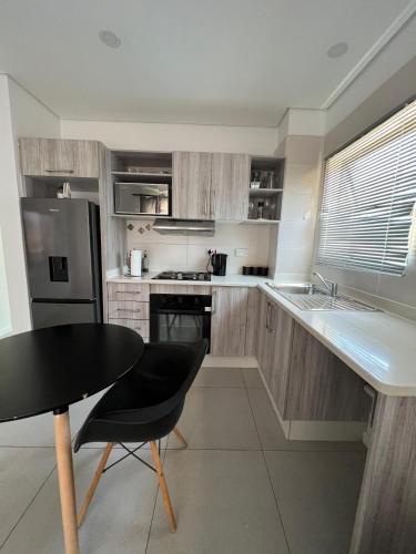 a kitchen with a black table and a refrigerator at Cozy One-bedroom Apartment near GrandPalm Resort Block 5, Gaborone, Botswana in Mogoditshane