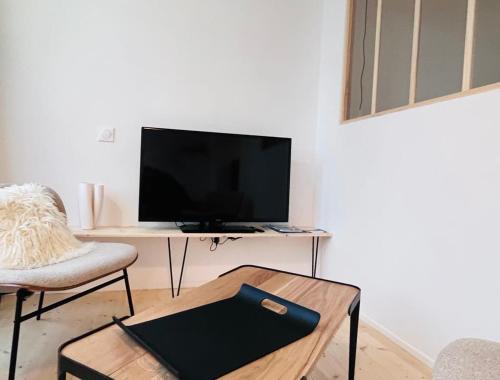 - un salon avec un bureau, une télévision et une table dans l'établissement Ker Alinec L Atelier, à Paimpol