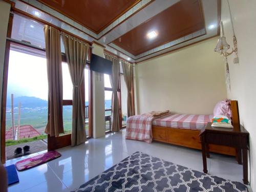 a bedroom with a bed and a large window at Agriya Lubis 2 room in Diyeng