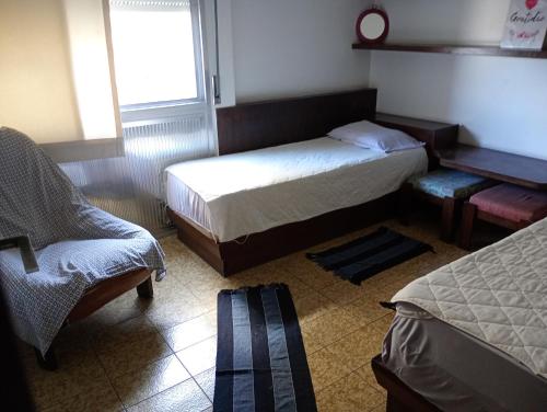 a bedroom with two beds and a chair and a window at PITANGUEIRAS LINDO FRENTE AO MAR 4 QUARTOs in Guarujá