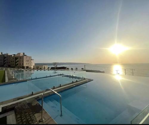 Una piscina con la puesta de sol sobre el agua. en Departamento con vista al mar, en Viña del Mar