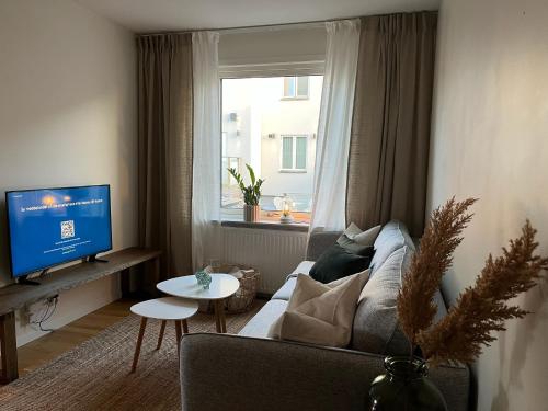 a living room with a couch and a tv and a window at Mindre lägenhet med stora möjligheter in Alingsås