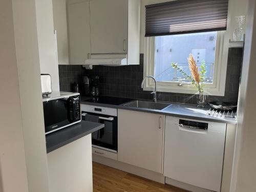 a white kitchen with a sink and a microwave at Mindre lägenhet med stora möjligheter in Alingsås