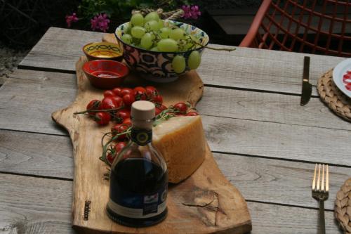 a bottle of wine on a cutting board with a bowl of grapes at Casale delle farfalle in Tornolo