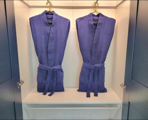 d'un placard avec trois chemises violettes exposées dans l'établissement Golden Royal - Studio Haut de Gamme, à Lyon