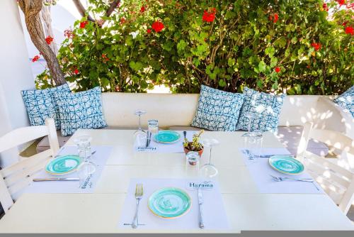 a white table with blue plates and napkins at Harama Hotel Schinousa in Skhoinoussa