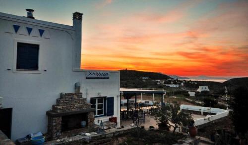 a building with a fireplace in front of a sunset at Harama Hotel Schinousa in Skhoinoussa