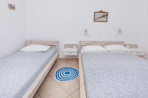 two twin beds in a room with a rug at Harama Hotel Schinousa in Skhoinoussa