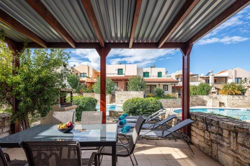 Un patio con mesa y sillas y una piscina. en Villa Lea, stylish, with common pool, en Chania