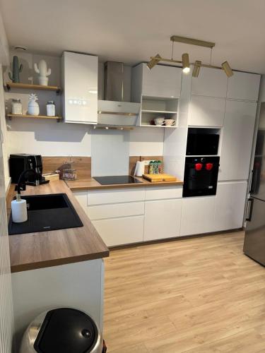 une cuisine avec des armoires blanches et un réfrigérateur noir dans l'établissement Maison des chênes, à Bavilliers