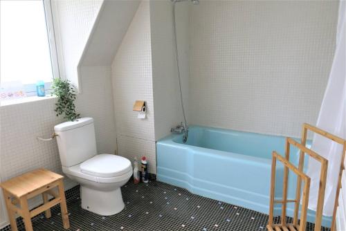 La salle de bains est pourvue de toilettes et d'une baignoire bleue. dans l'établissement Maison VUE MER avec jardin à 800m de la plage à TREBEURDEN REF-683, à Trébeurden
