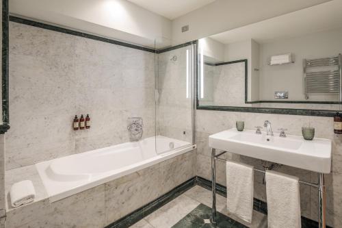 a white bathroom with a tub and a sink at Donna Camilla Savelli - VRetreats in Rome