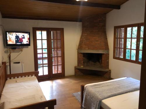 un salon avec une cheminée et une télévision dans l'établissement Pousada SerTão de Minas, à Conceição da Ibitipoca