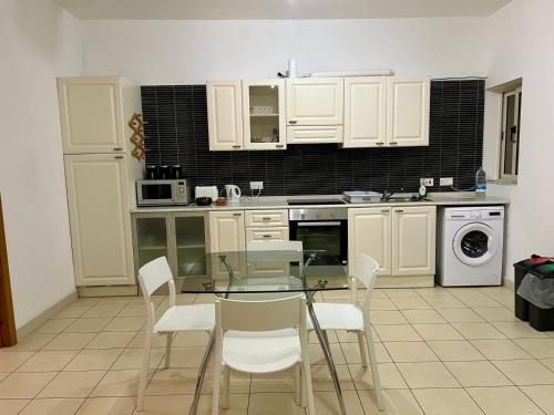 a kitchen with white cabinets and a glass table and chairs at Centrally Located Gzira in Il-Gżira