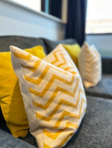 two yellow and white pillows sitting on a couch at Apartment Twenty Three Staines Upon Thames - Free Parking - Heathrow - Thorpe Park - Studio in Staines