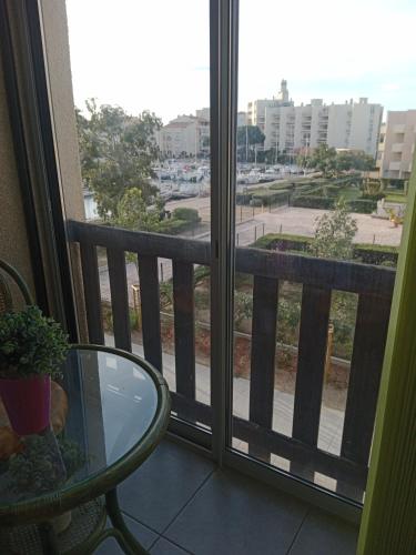 d'un balcon avec une table en verre et une vue sur la rue. dans l'établissement T2 au LAMPARO, à Leucate-Plage