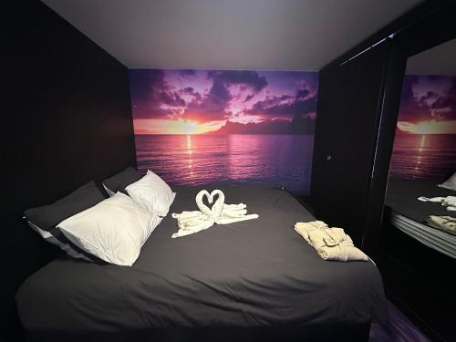 a bed in a room with a painting of a sunset at Nid d'amour in Trouville-sur-Mer
