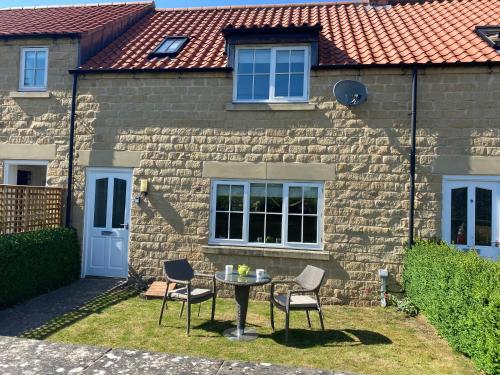 a table and chairs in front of a brick house at pottergate mews in Helmsley