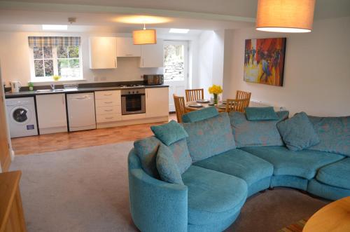 a living room with a blue couch and a kitchen at pottergate mews in Helmsley