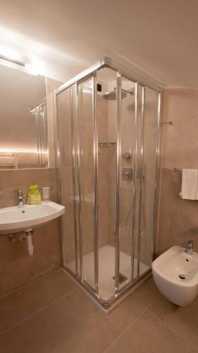 a bathroom with a shower and a toilet and a sink at Hotel Bellevue in Canazei