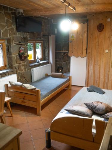 a bedroom with two beds and a stone wall at Domek Hubertus Chochołów in Chochołów