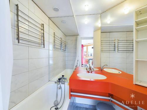 een badkamer met twee wastafels, een badkuip en een rood aanrechtblad bij Charmant 2P avec Parking, Balcon, près des Pistes et Commerces à Montvalezan - FR-1-398-509 in La Rosière