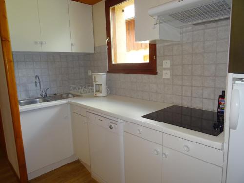 une cuisine avec des armoires blanches et un évier dans l'établissement Les Prés-Ronds, à La Chapelle-en-Valgodemard