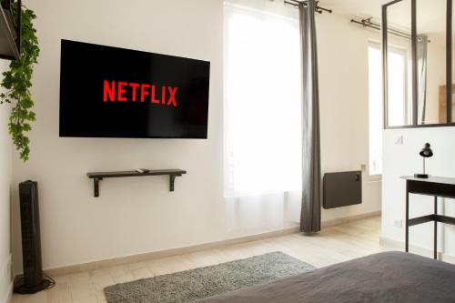- un salon avec un panneau netflix sur le mur dans l'établissement L'Atelier Contemporain - Porte de Paris, Stade de France, Aéroport CDG, à Aubervilliers