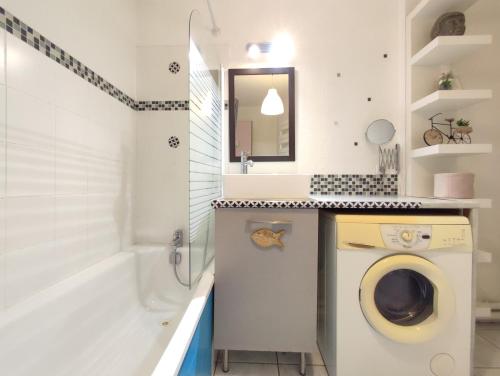une salle de bain avec un lave-linge et une baignoire dans l'établissement Roseraie T2 Wifi Parking Clim, à Toulouse