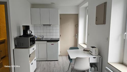 a small white kitchen with a table and a microwave at Studio Paimpol centre historique in Paimpol